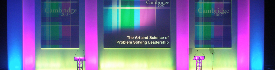 Purple, green and blue stage with three screens and speaker plinths